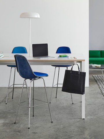 A standing-height Layout Studio table in white with an integrated Ode lamp with Eames molded fiberglass stools in dark blue.