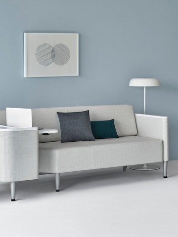 A Palisade Flop Sofa in light gray textile with white solid surface arm caps and white adjustable table with Durawrap top. A Palisade Flop Sofa in light gray textile with white solid surface arm caps and white adjustable table with Durawrap top.