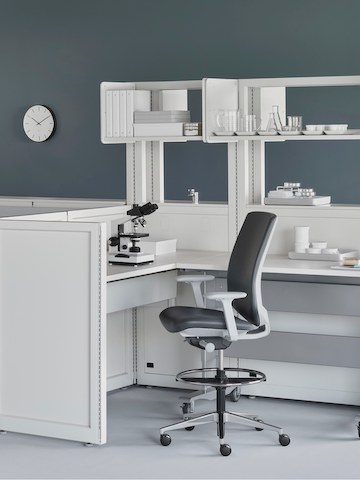 A medical laboratory setting containing Co/Struc System with a height-adjustable process table and a dark gray Verus Stool. A medical laboratory setting containing Co/Struc System with a height-adjustable process table and a dark gray Verus Stool.