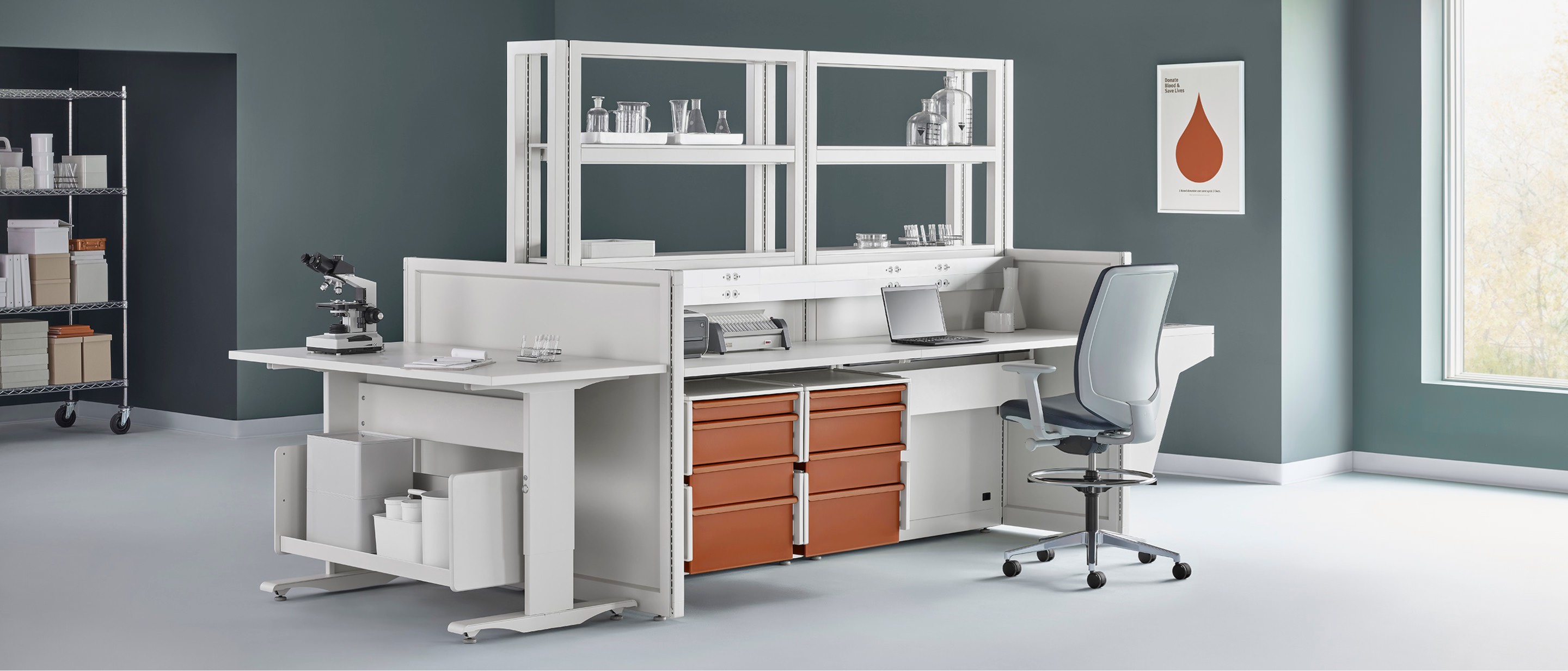 A lab setting with a Co/Struc System workstation and shelving in the center with a Verus work stool. A lab setting with a Co/Struc System workstation and shelving in the center with a Verus work stool.