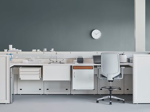 A laboratory setting featuring a white Co/Struc System with below-surface storage and a gray Verus Stool in a medical laboratory.