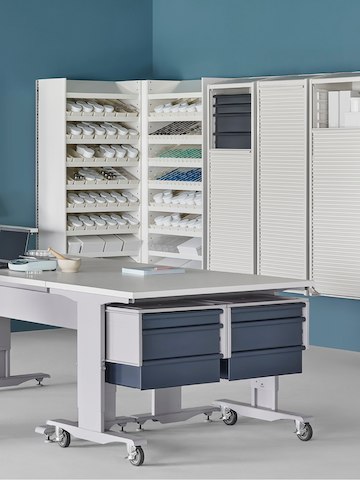 A pharmacy environment with a Co/Struc System dispensing system, storage lockers, and process tables.