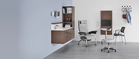An exam room with wall-mounted Mora System and a patient chair, stool, and side chair around an Intent Solutions table and wall unit.
