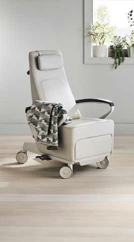 Three-quarter, right view of a light gray Ava recliner with a blanket draped over the arm.