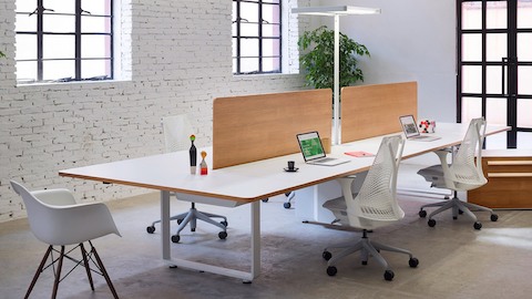 白いSaylオフィスチェアとペアになって、白い作業面と木目調のプライバシースクリーンを備えたArrasベンチ。