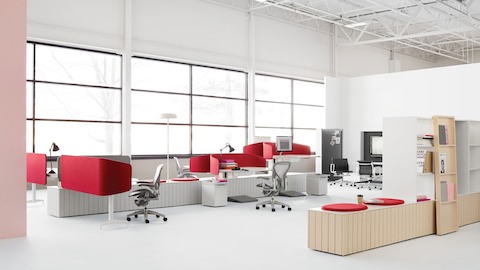 Ein offenes Büro in einem Industriegebäude mit grauen Aeron Stühlen an Locale-Arbeitsplätzen mit roten Sichtblenden. Ein offenes Büro in einem Industriegebäude mit grauen Aeron Stühlen an Locale-Arbeitsplätzen mit roten Sichtblenden.