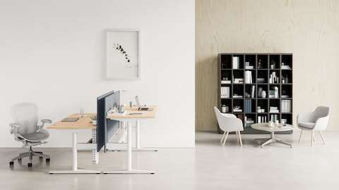 Back-to-back Ratio desks at both standing and seated heights with a light grey Aeron Chair. A grey Saiba Chair and an occasional-height Civic Table are shown in front of a Port Storage System. Back-to-back Ratio desks at both standing and seated heights with a light grey Aeron Chair. A grey Saiba Chair and an occasional-height Civic Table are shown in front of a Port Storage System.