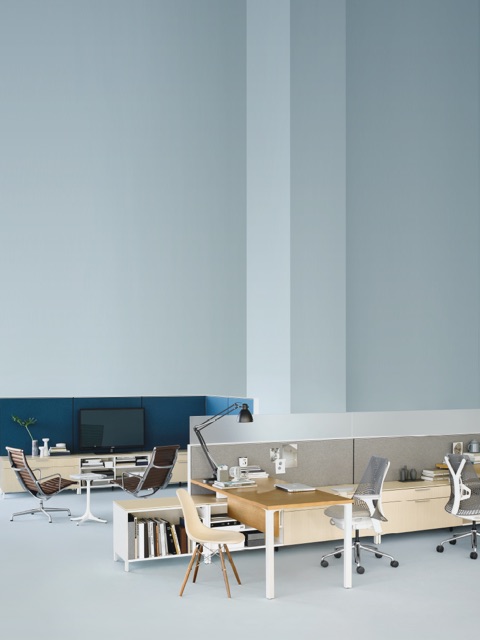 两个棕色皮革Eames Aluminum 组合椅子和一个Nelson Pedestal桌子在一个开放的工作场所固定休闲区。