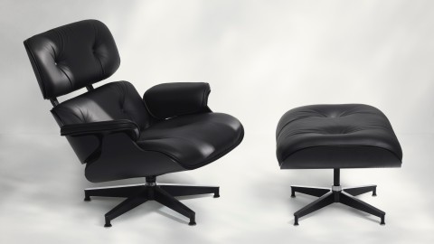 An Eames Lounge Chair and Ottoman with black leather upholstery and a black molded plywood shell.