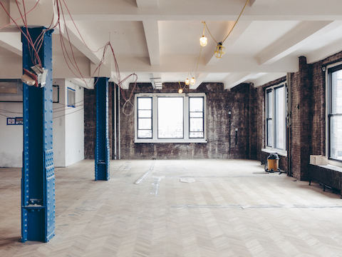 A before photo of Harry's workplace, showing a barren brick-walled room.