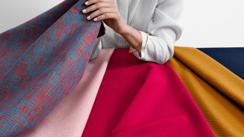 A woman's hand grasps colorful material samples. A woman's hand grasps colorful material samples.