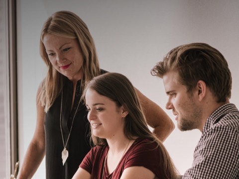 Two women and a man review a project at work. Two women and a man review a project at work.