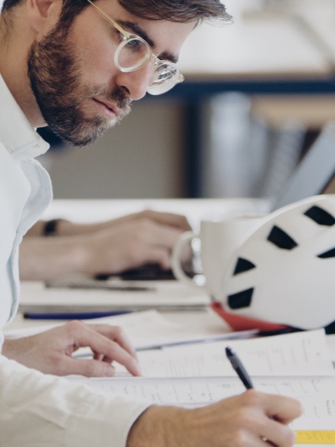 Close view of a man looking over paperwork on a desk.