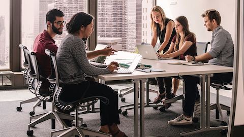 People converse at a table as they are seated at Setu Chairs.