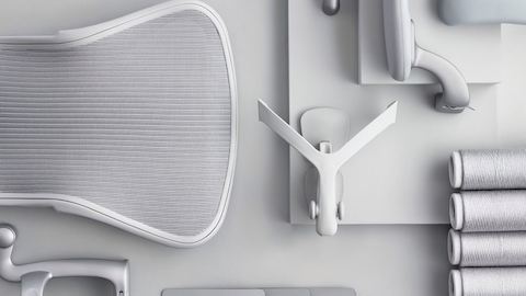 Overhead view of a disassembled light grey Aeron office chair, including five-star base, arms and back support.