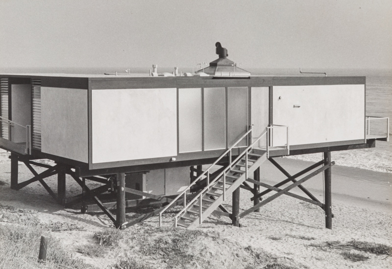 Exterior view of Craig Ellwood's Hunt House showcasing its setting on stilts on the beach in Malibu, California.