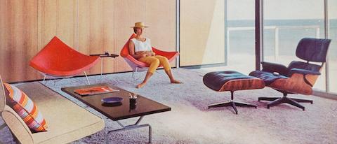 A woman sits in one of a pair of orange-pink Nelson Coconut Chairs in the sunny living room of a mid-century modern home in Malibu. An Eames Lounge Chair and Ottoman and Eames Sofa Compact are nearby.