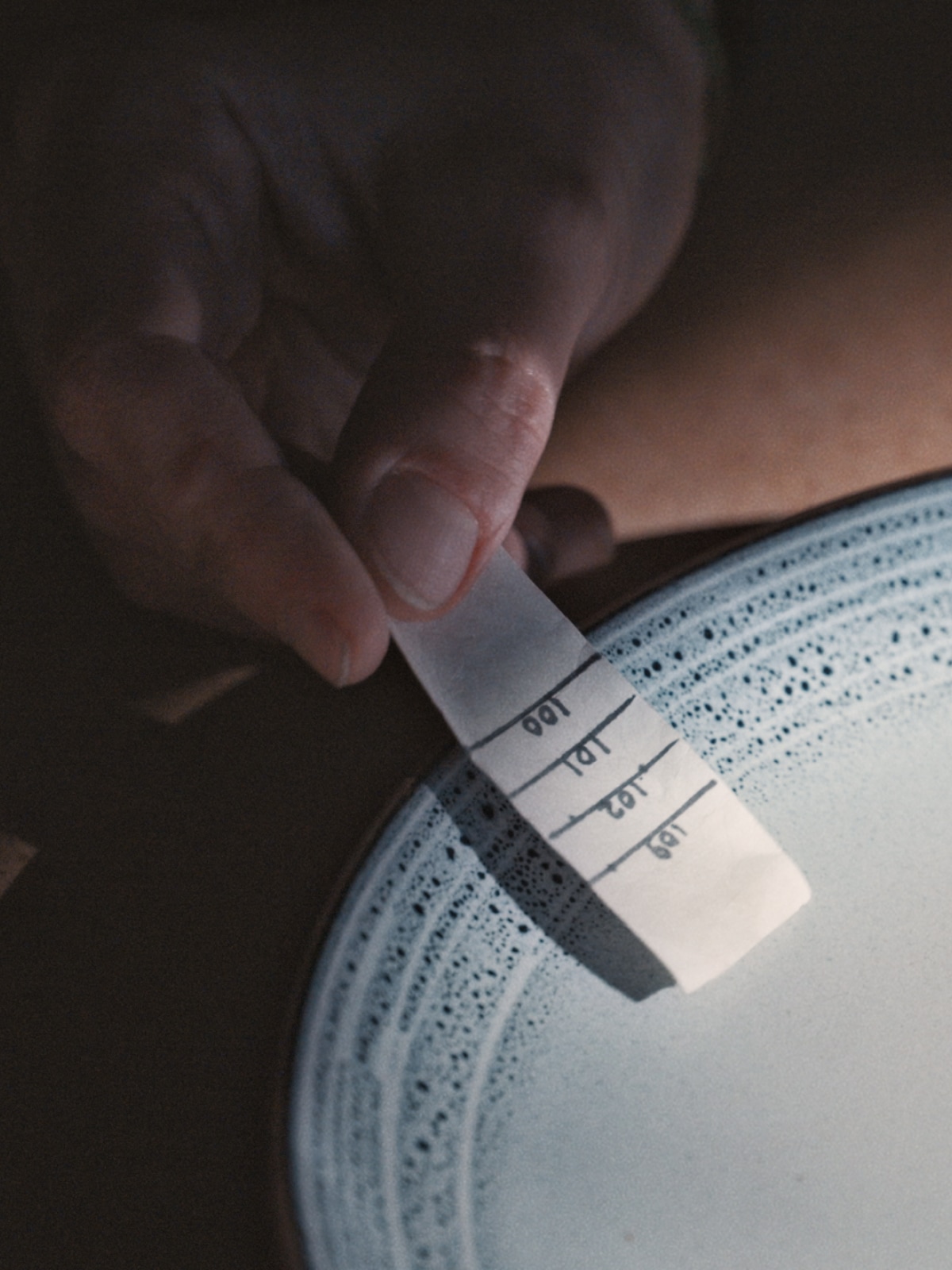 A hand holds a label with number markings against a finished plate.
