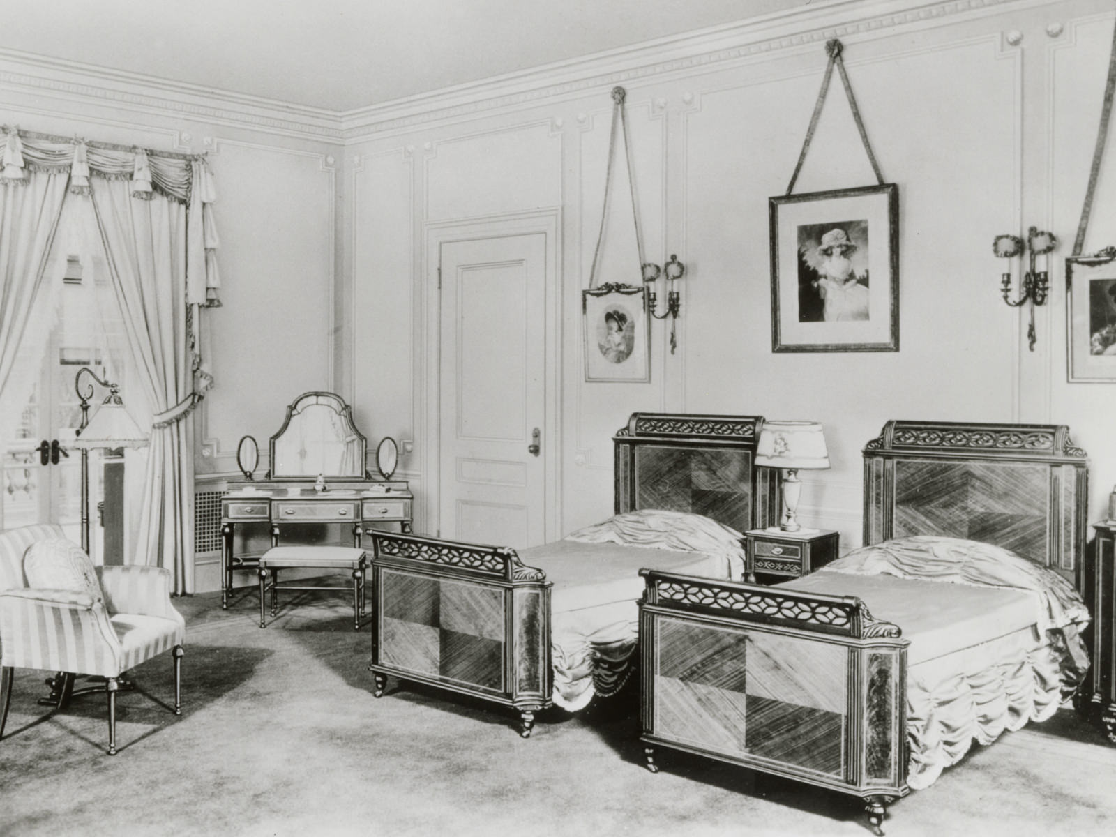 仿古卧室套装家具，包括以拼花镶木饰面为特色的一对单人床、床头桌、座椅和梳妆桌。