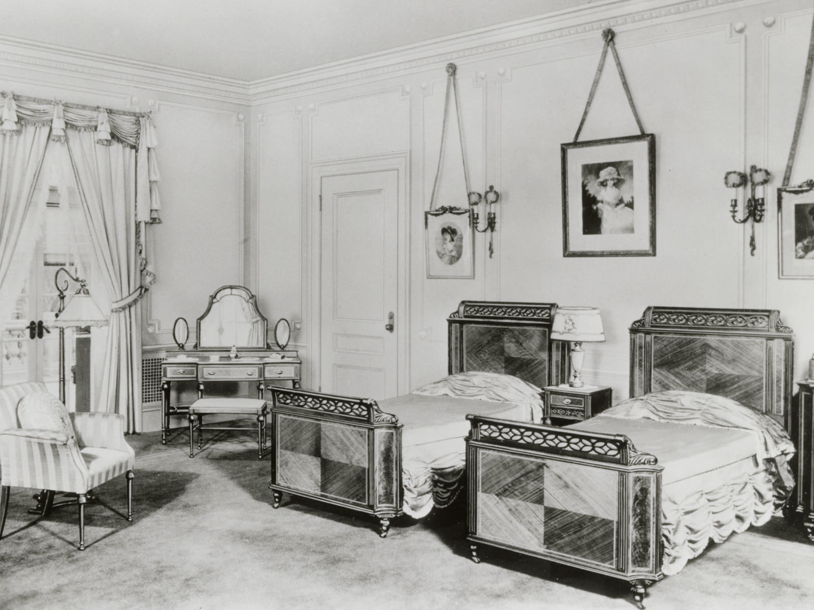 An antique reproduction bedroom suite including two twin beds, night stand, chair and dressing table featuring parquet wood finish.