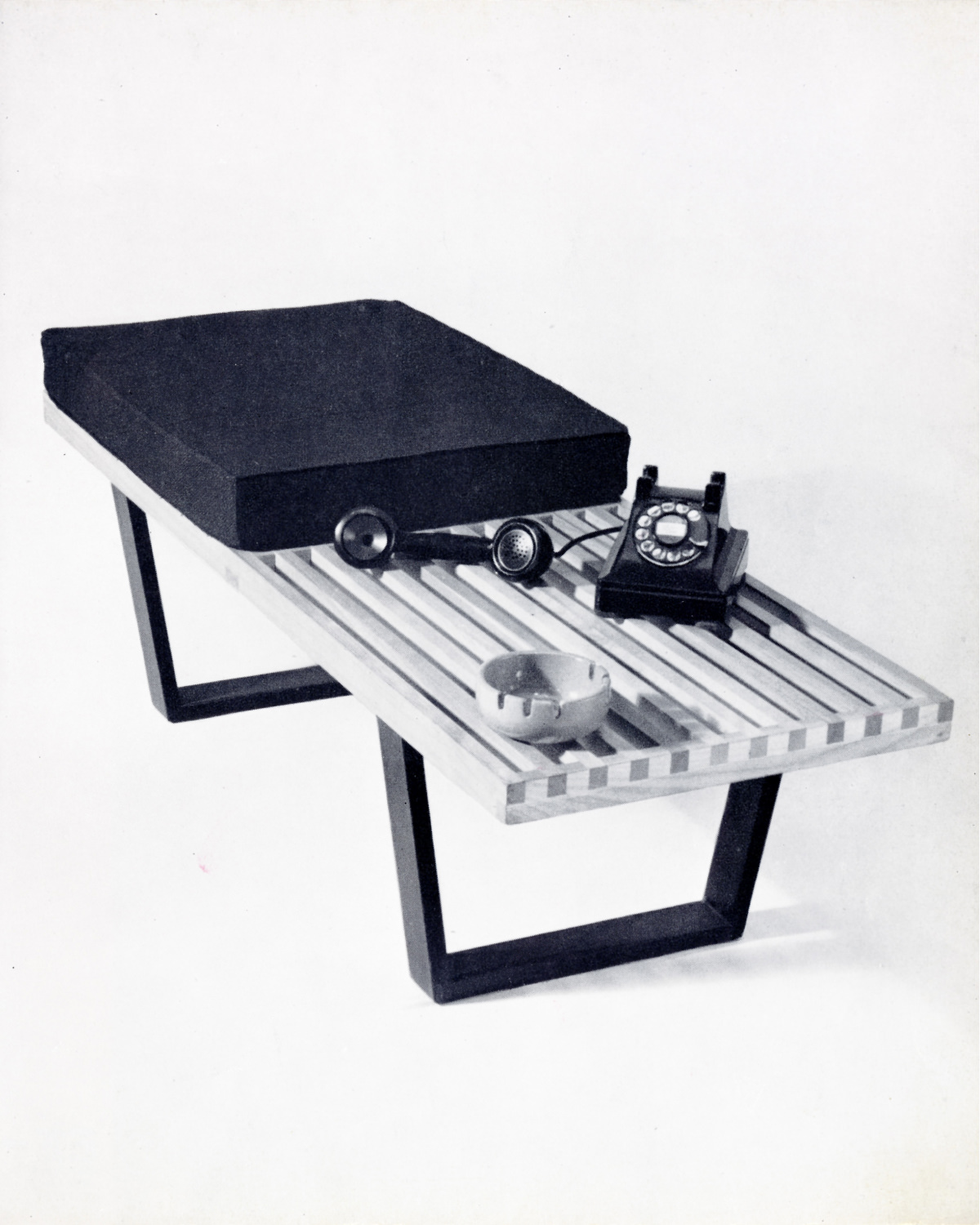 Nelson platform bench with a seat cushion positioned on the left half of the bench, next to a rotary telephone and ashtray positioned on the right side.