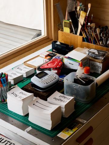A smattering of office supplies are stacked in neat piles on top of a cabinet.