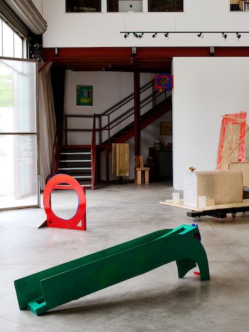 Inside Marta gallery's double-height gallery space, with whtie walls, dark red metal stairs, and cement floor, with artwork placed intentionally around the floorplate.