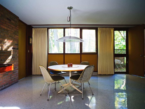 The dining area on the opposite side of the living room features upholstered Eames Wire Chairs and a Nelson Table‚Äîboth  customized to a lower height. Corner recreated the pendant light based on original drawings and photographs.