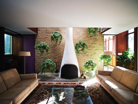 Corner was able to acquire most of the original living room furniture selected by the Nelson Office, including these Herman Miller sofas. The fireplace and hanging plants are lit by skylights above.