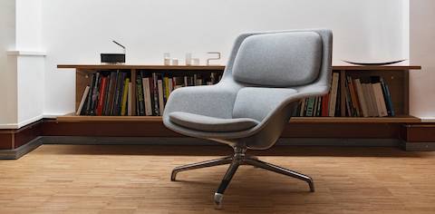 A gray Striad Lounge Chair in front of a bookshelf.