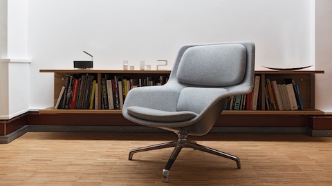 A gray Striad Lounge Chair in front of a bookshelf. Select to go to a WHY Magazine interview of designers Jürgen Laub and Markus Jehs.
