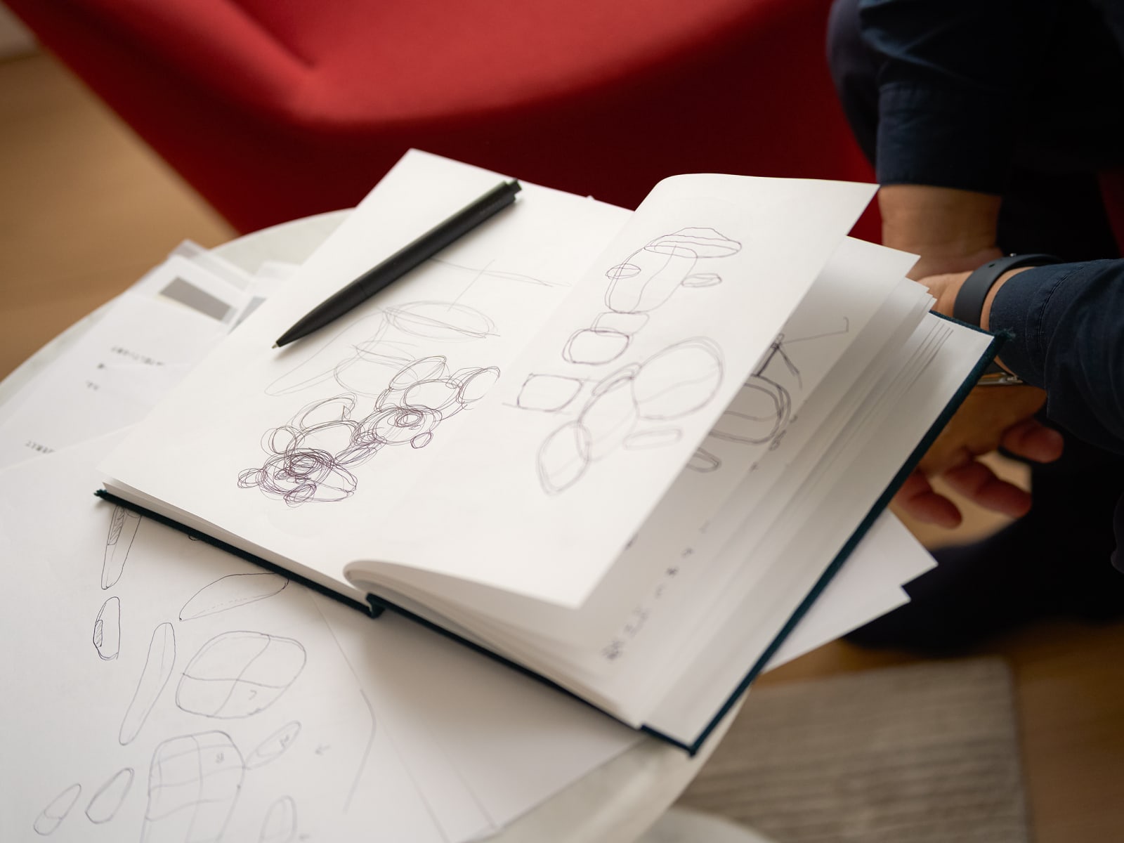 A sketch book from Naoto Fukasawa open to a page with designs for the Asari chair.