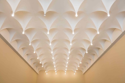 Alexander Girard designed the ceiling in the lobby of the Cummins Office at 432 Washington Street to feature a grid of vacuum-formed white stalactites, each of which come to a point with an exposed light bulb.