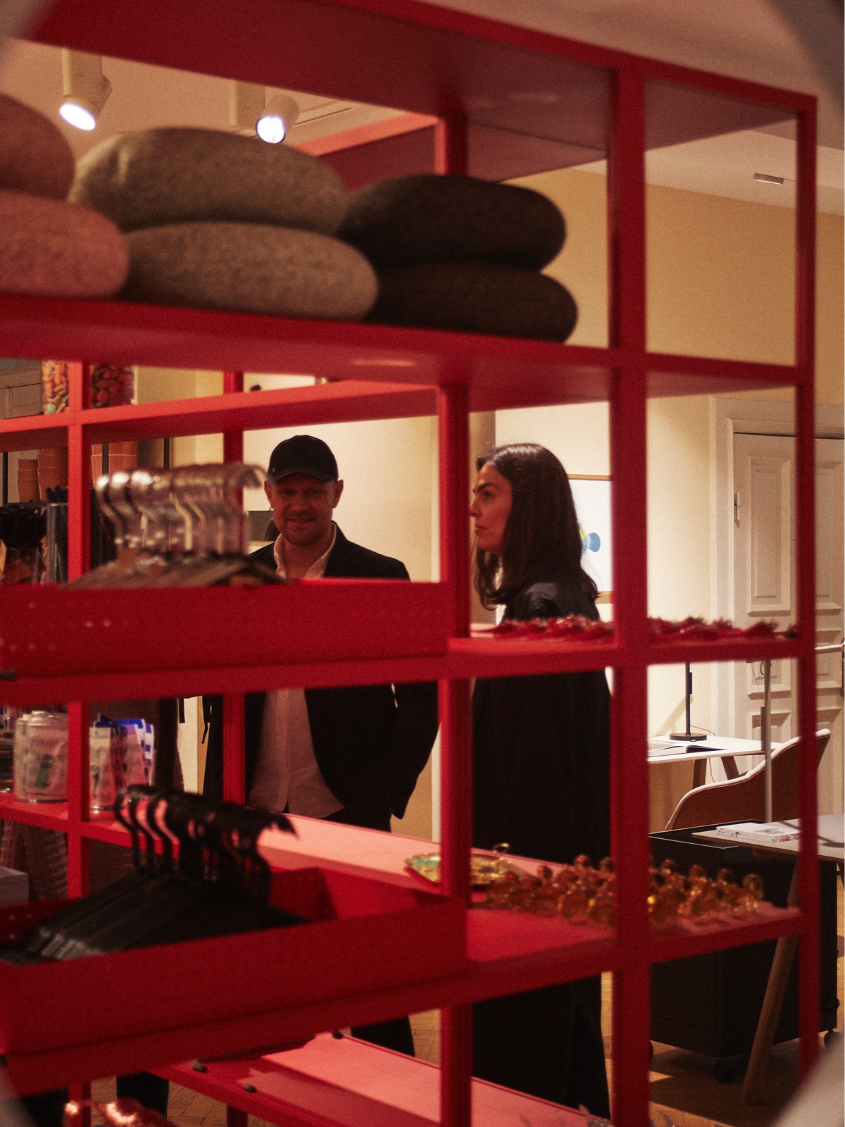 Rolf and Mette Hay are seen in their flagship store, HAY House, through a red shelf dotted with accessories.