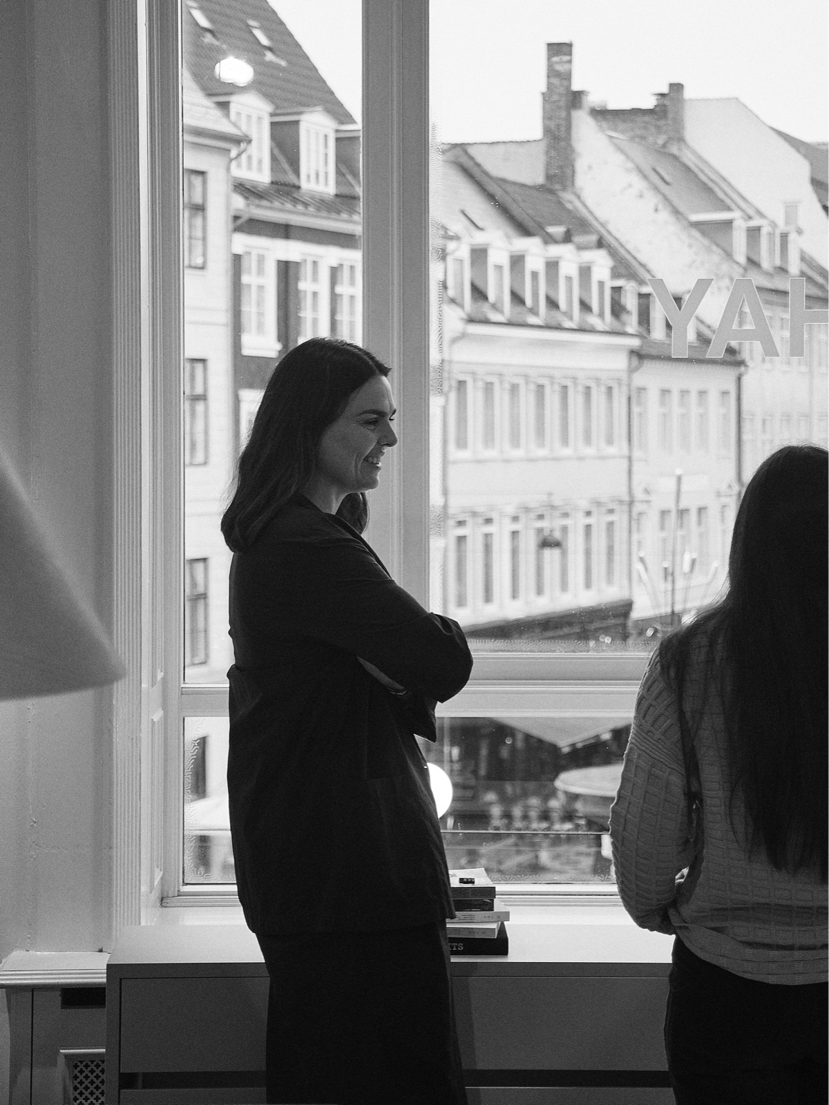 A black and white photograph of Mette Hay, shown from the side, and the back of Amy Auscherman at HAY House in Copenhagen.