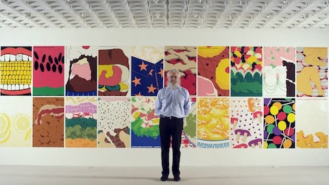 Graphic designer Steve Frykholm stands before a wall of posters. Select to go to a WHY Magazine interview of Frykholm.