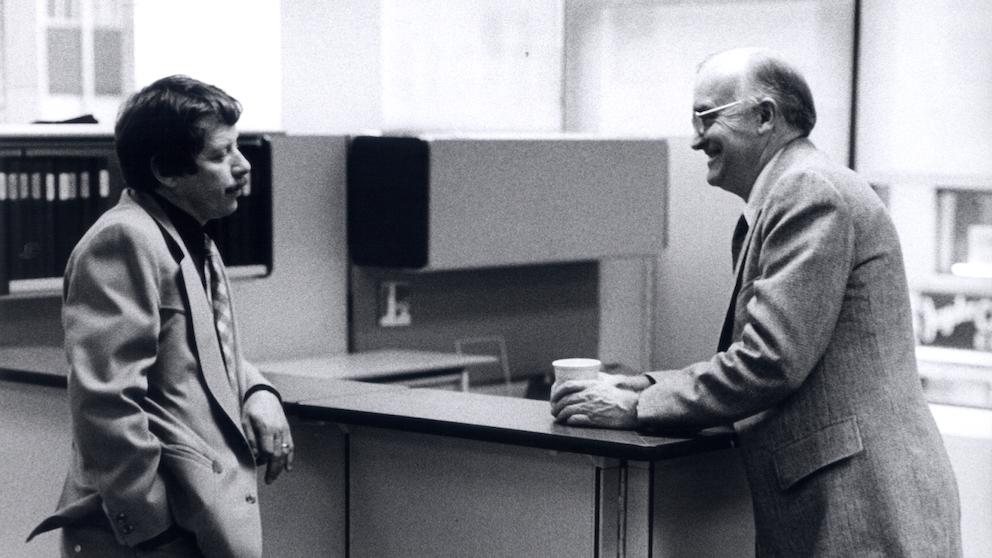 Black and white candid photo of Jack Kelley and Robert Propst, leaning on Action Office surface. 