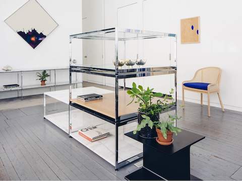 Stacked H Frame Coffee Tables in a mix of marbles, glass, and wood display flatware and other artifacts from Bennett’s oeuvre.