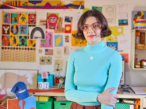 Olimpia Zagnoli in her Milan studio, in front of a wall filled with her colourful artwork.
