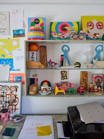 Three shelves filled with small, brightly coloured art and objects in Olimpia Zagnoli's studio.