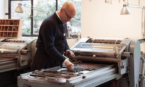 A man works with a printing press.
