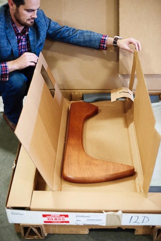 A man packages one leg of a Noguchi Table in a sustainable shipping container.