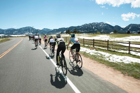 Several bicyclists ride toward the foothills in Boulder, Colorado.