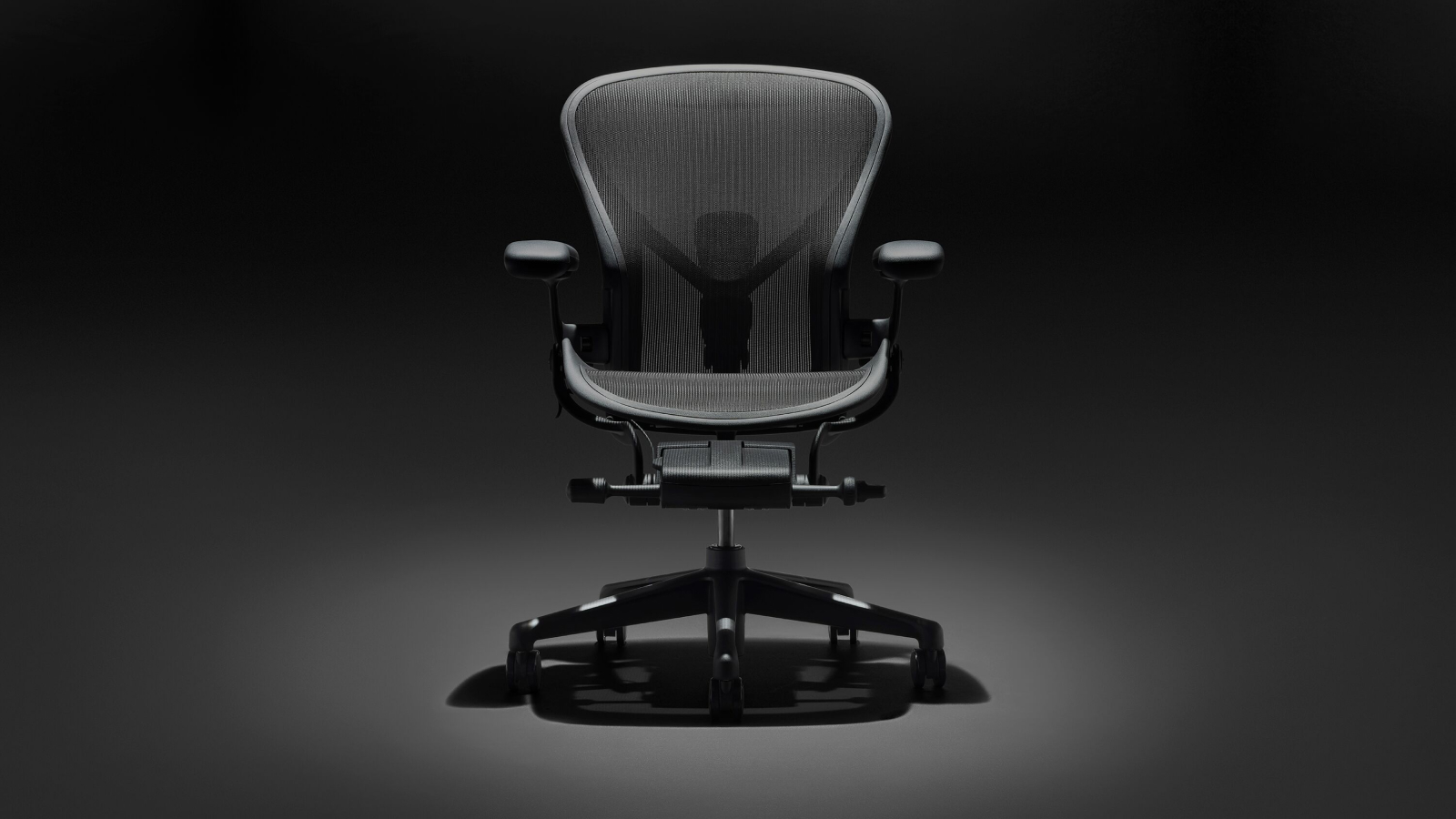 A black Aeron Chair on a black background, viewed from the front.