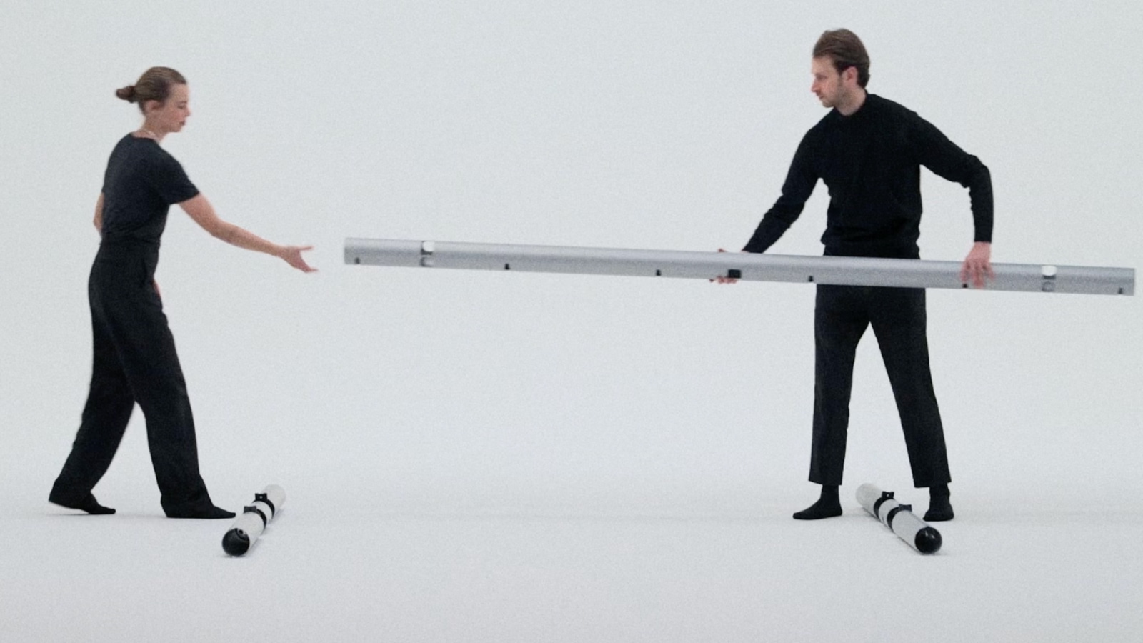 Two people holding a tubular aluminum frame.