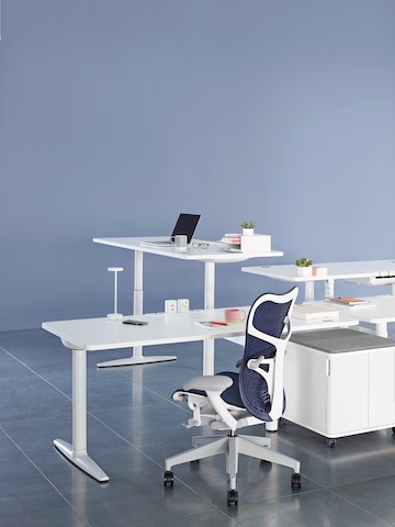 A blue Mirra 2 office chair situated amid a cluster of workpoints using sit-to-stand desks positioned at different heights.