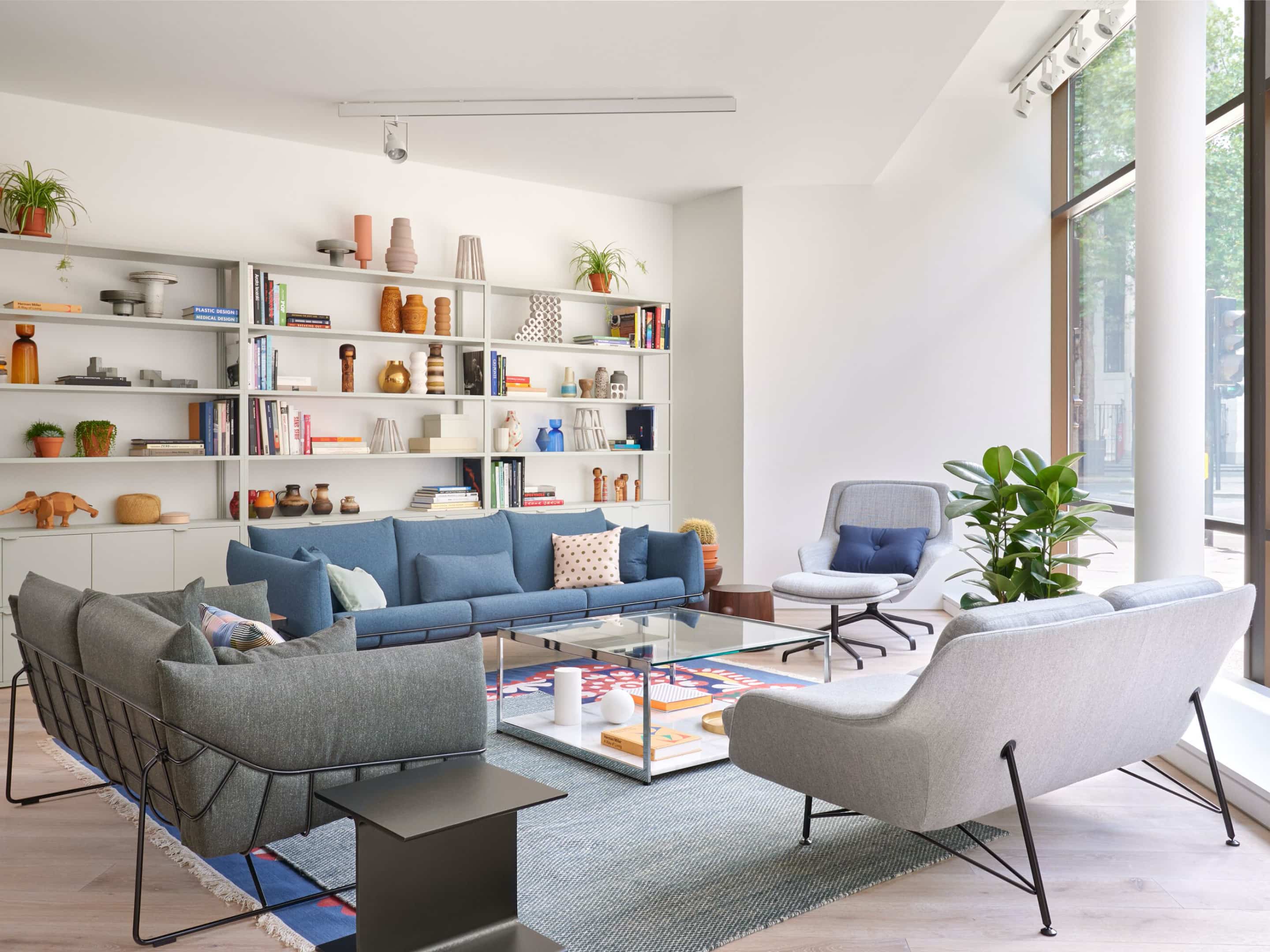 Collection of sofas, a lounge chair and side tables in front of a large bookcase.