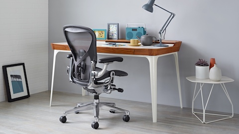 A residential workpoint featuring an Airia Desk, black Aeron office chair, and Polygon Wire Table. Select to shop the Herman Miller store and other online retailers.